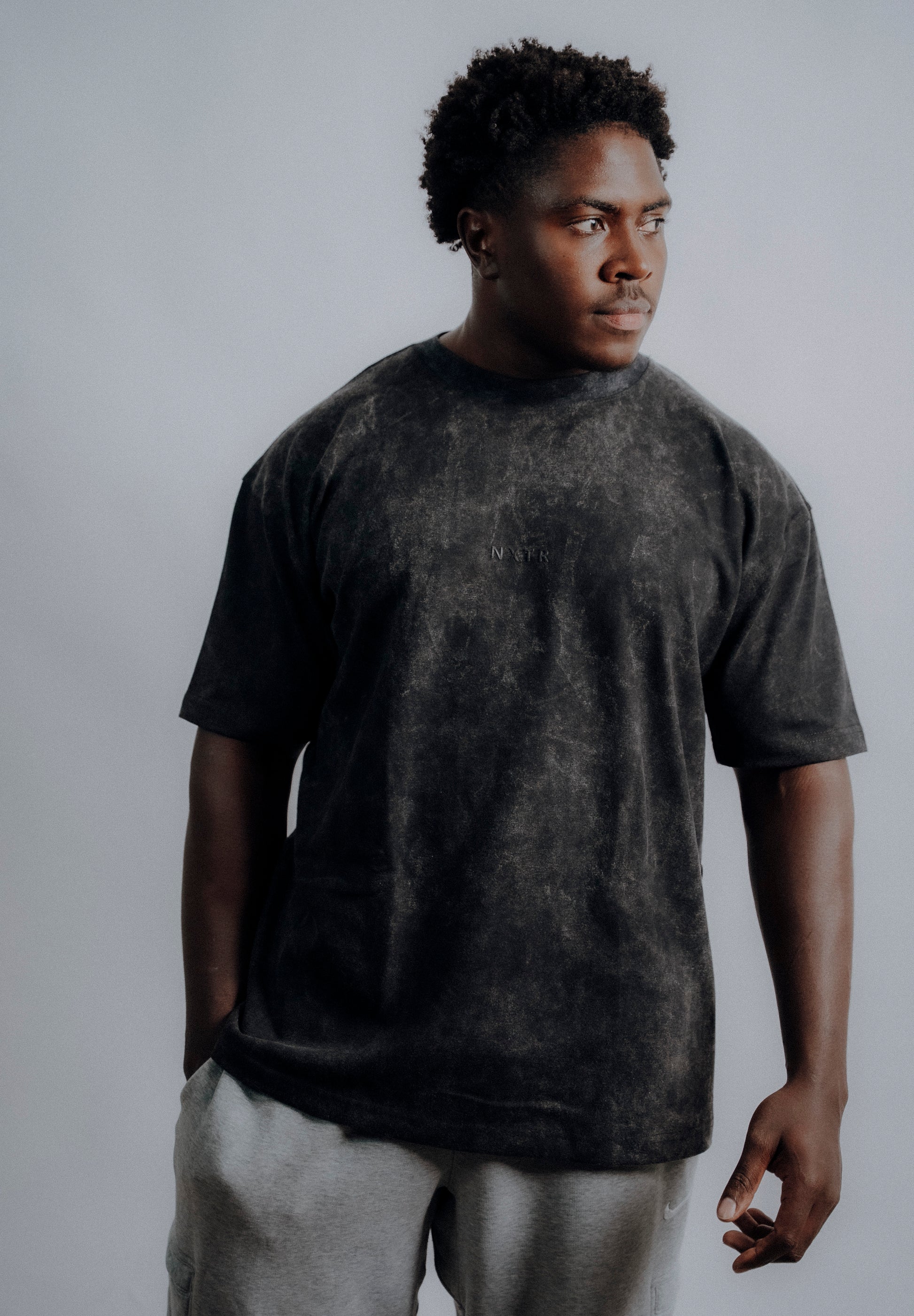 Man wearing a dark gray t-shirt against a plain background